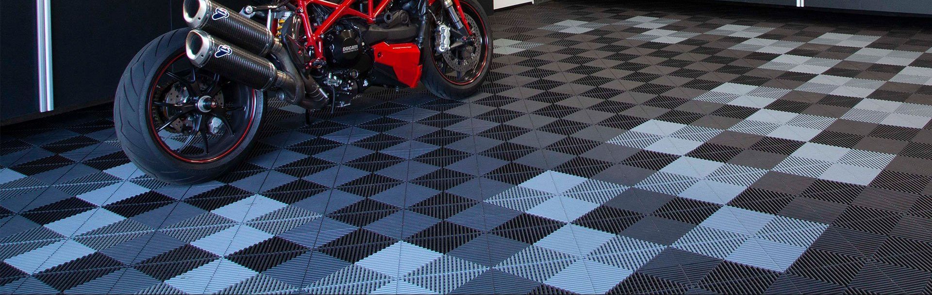 A motorcycle is parked on a interlocking floors in a garage.