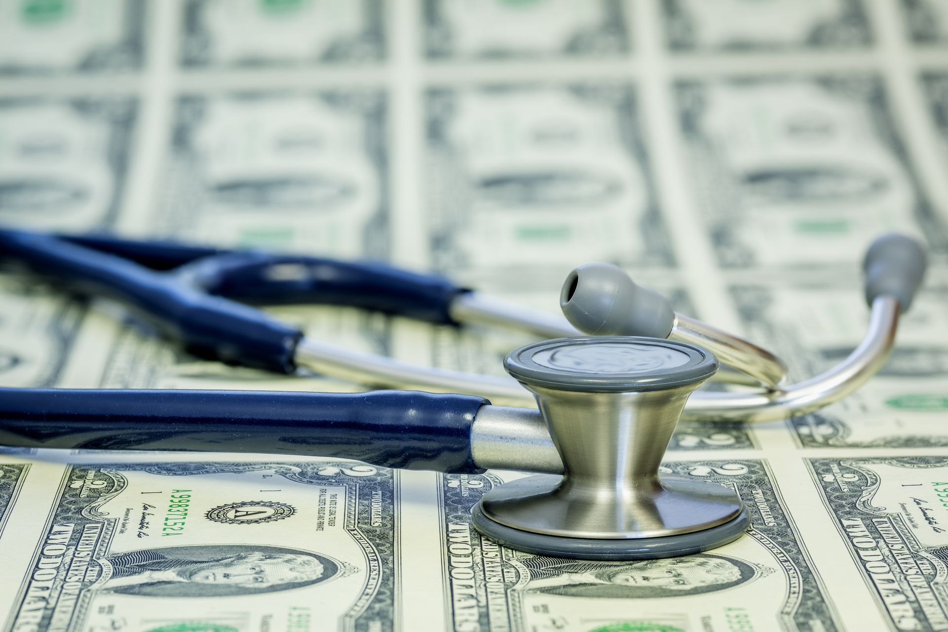 Stethoscope on a bed of US dollar bills, symbolizing healthcare costs.