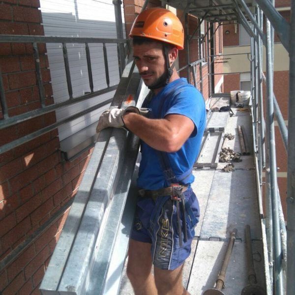 Un uomo che indossa una camicia blu e pantaloncini blu è in piedi su un'impalcatura