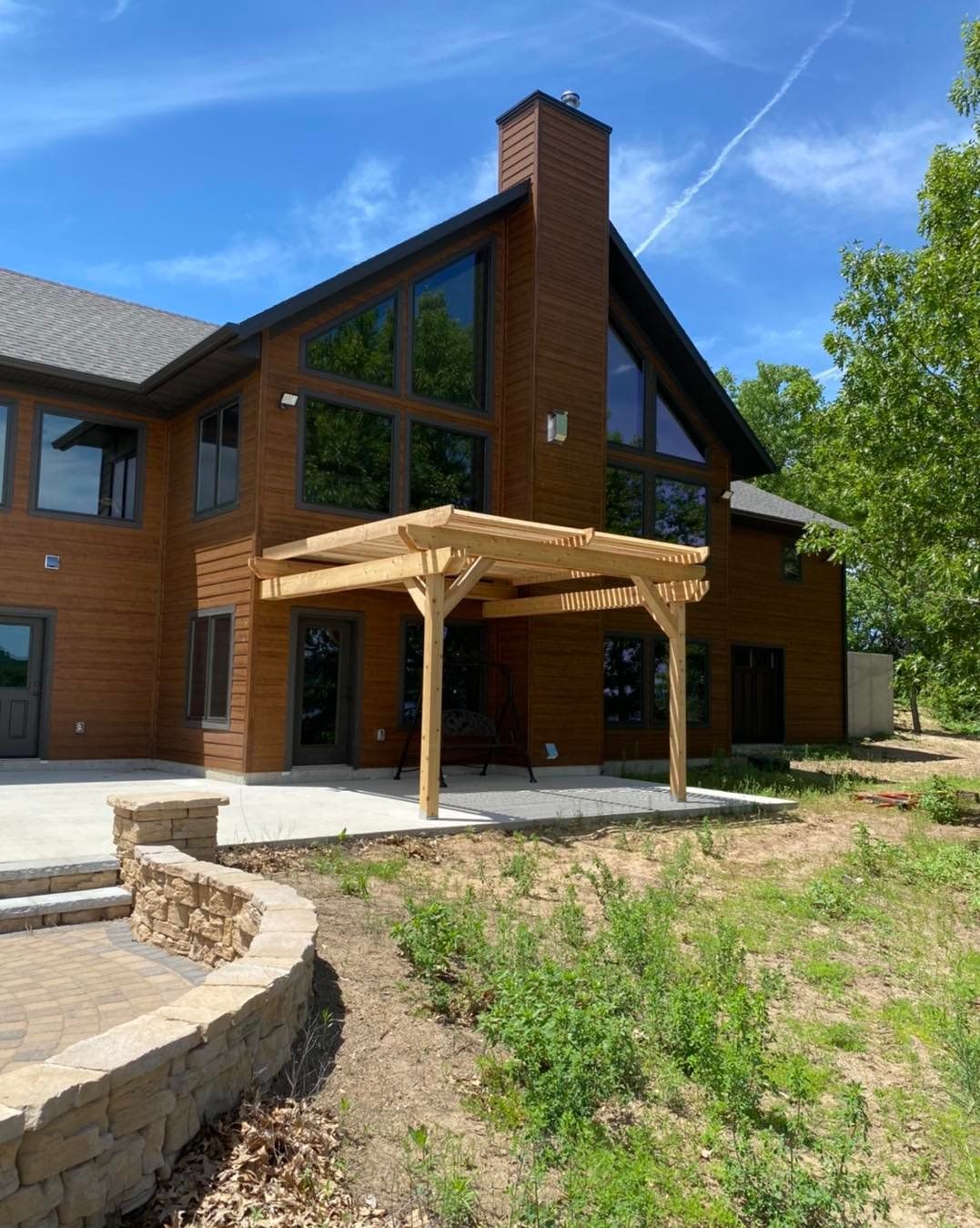 A large brick house with a newly built wooden pergola in front of it