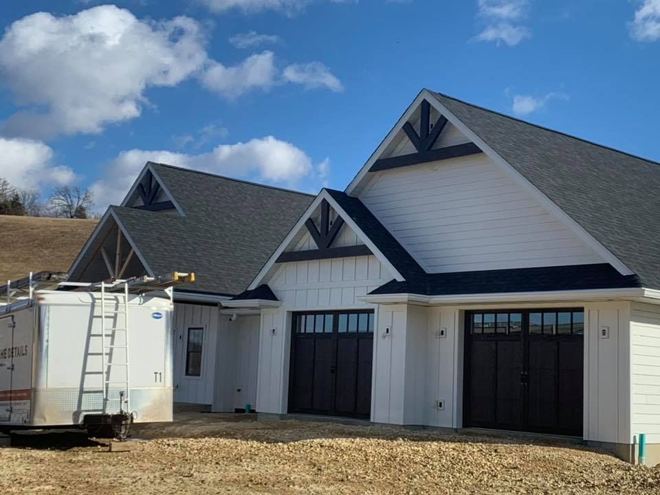 A white house with a black garage door is being built