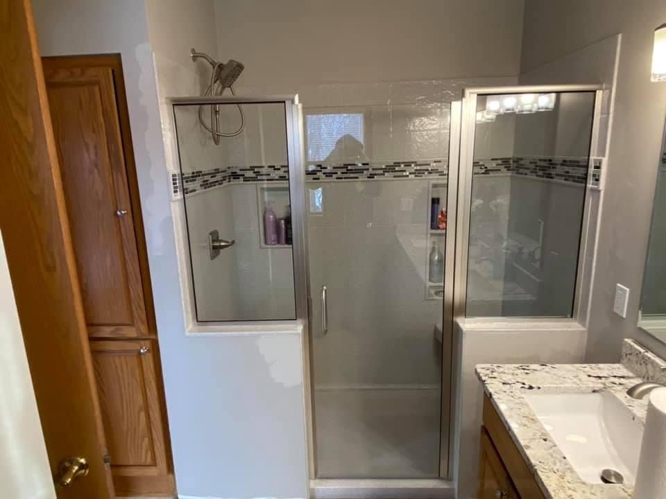 Bellevue bathroom renovation with a glass walk-in shower, accent tile, recessed storage, and granite vanity