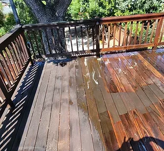 A wooden deck with a wooden railing and a tree in the background.
