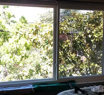 A bedroom with a large window looking out to trees