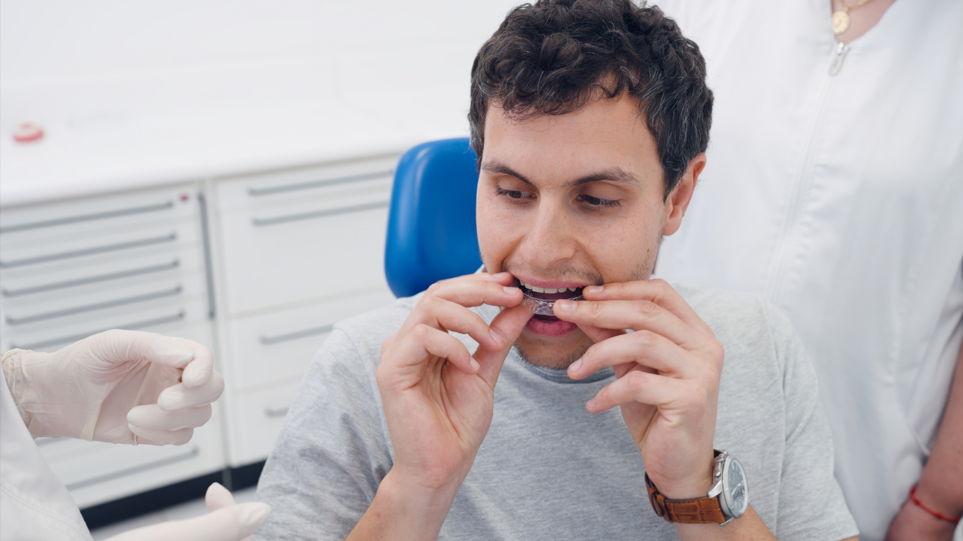 Dentist fitting clear aligners on a patient in a bright dental office