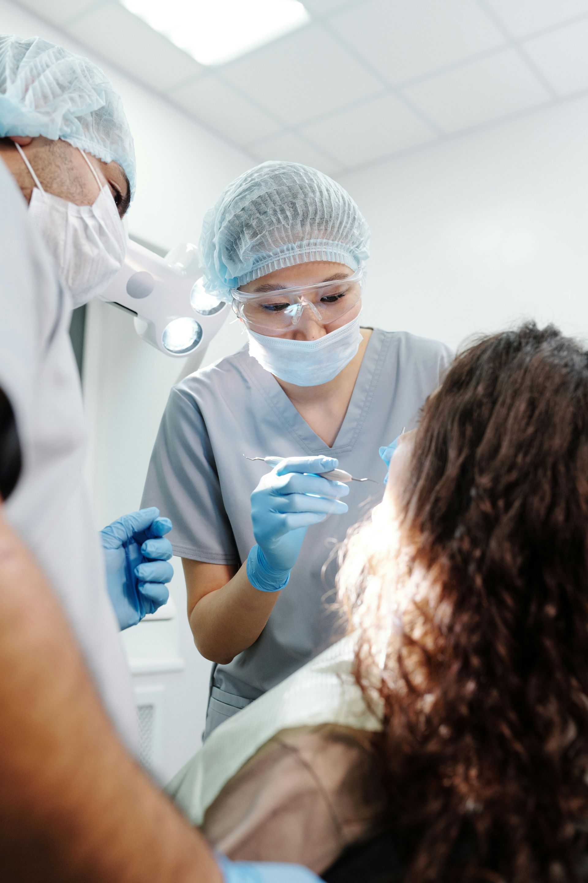 Dentists in masks and gloves treating a patient in a bright clinic