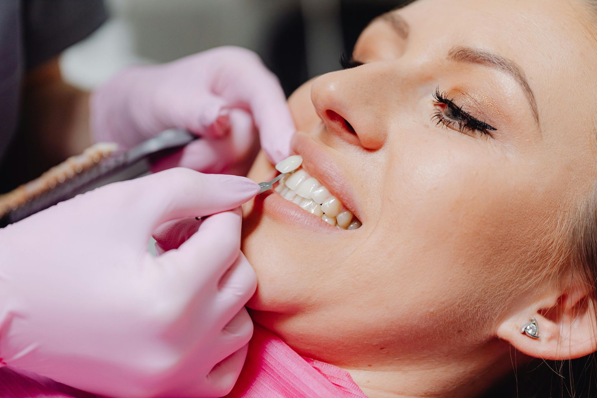 Dentist adjusting clear braces on a smiling patient in pink gloves