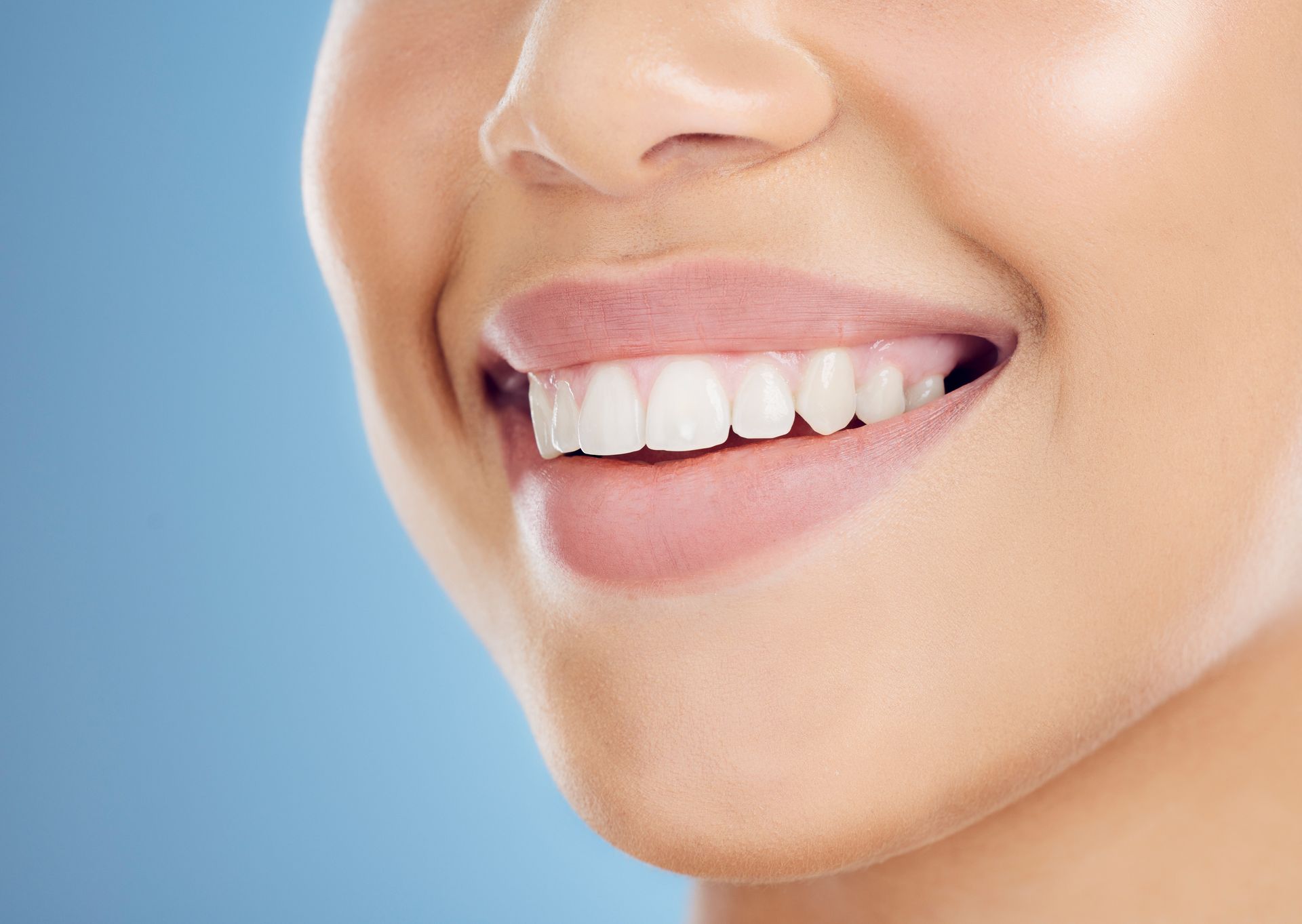 Close-up of a smiling mouth, showing bright white teeth and pink lips.