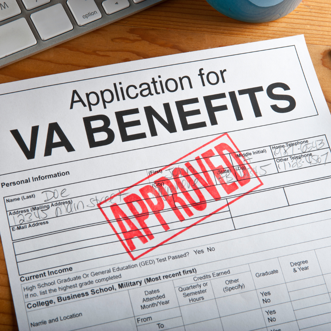 An application for va benefits is sitting on a wooden table next to a keyboard.