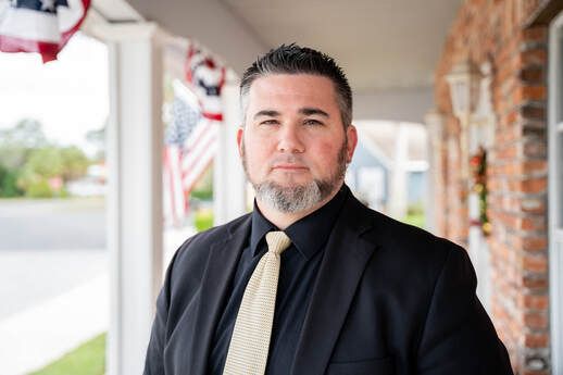 A man in a suit and tie is standing on a porch.