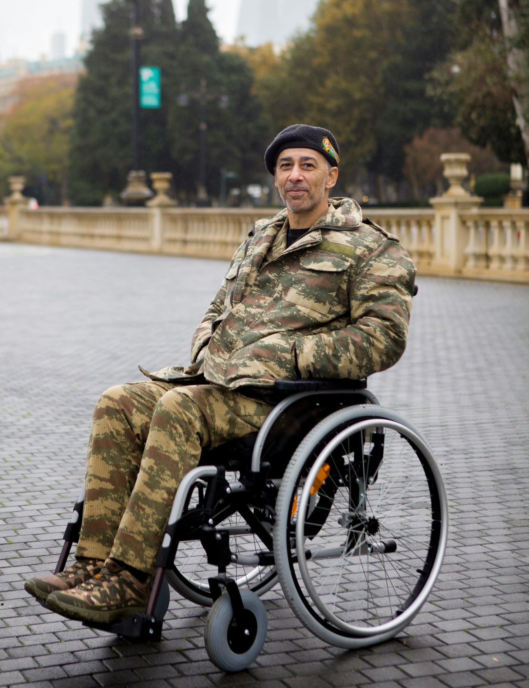 A man in a camouflage uniform is sitting in a wheelchair.