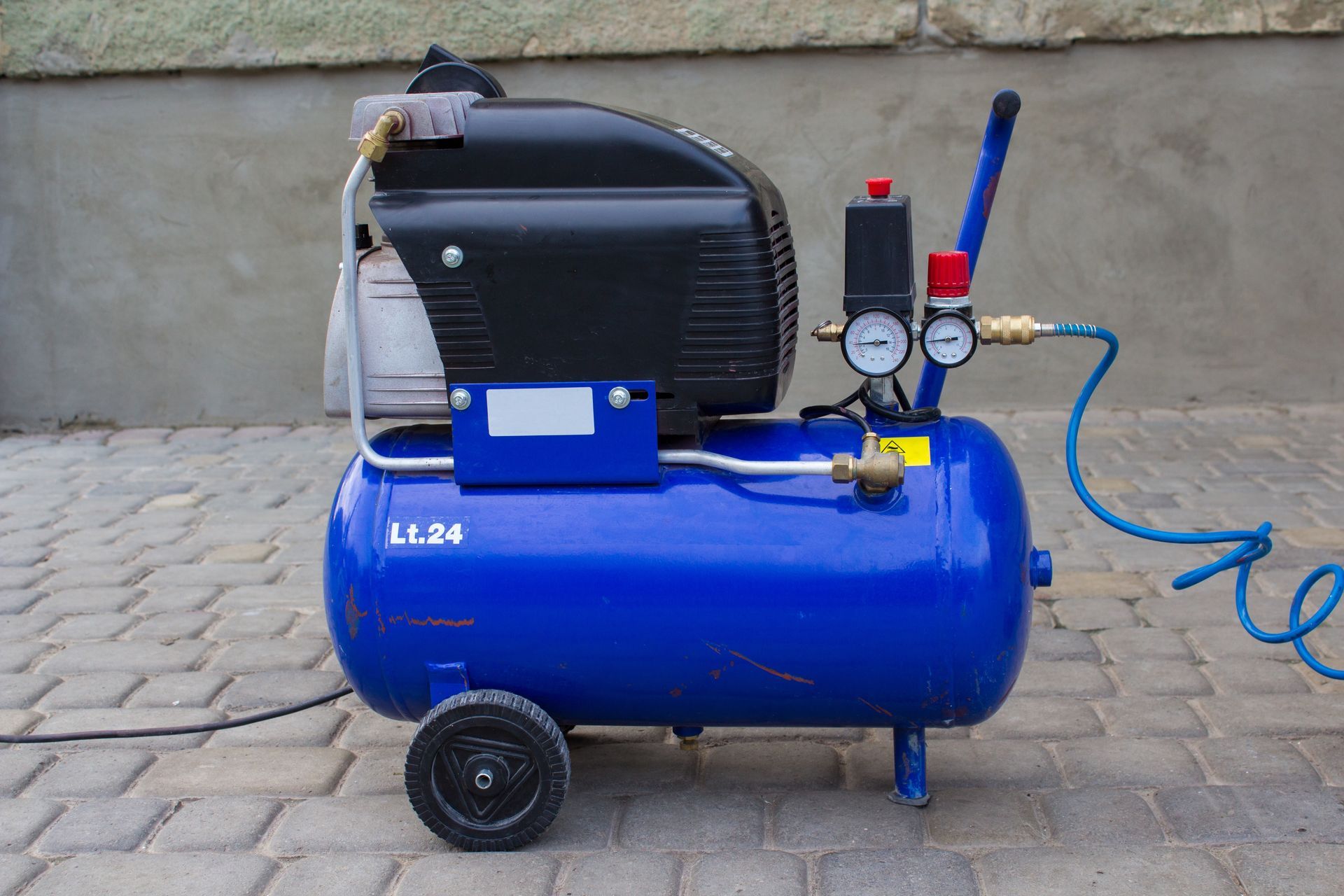 Portable Air Compressor With Gauges and Hose on a Paved Surface — Max Fox Electrical in Armidale, NSW