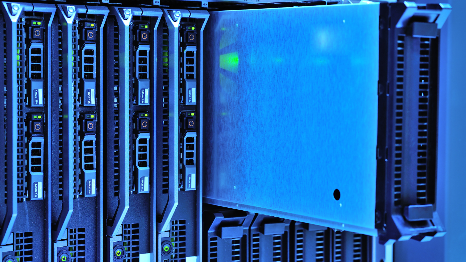 A row of vertical server blades in a data center, with one unit extending out, illuminated by blue ambient light.