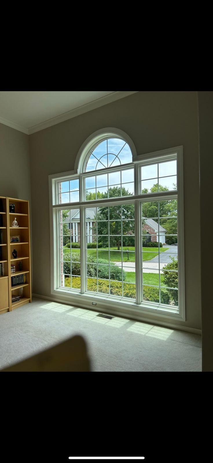 Tall arched picture window with grilles, seen from inside a living room