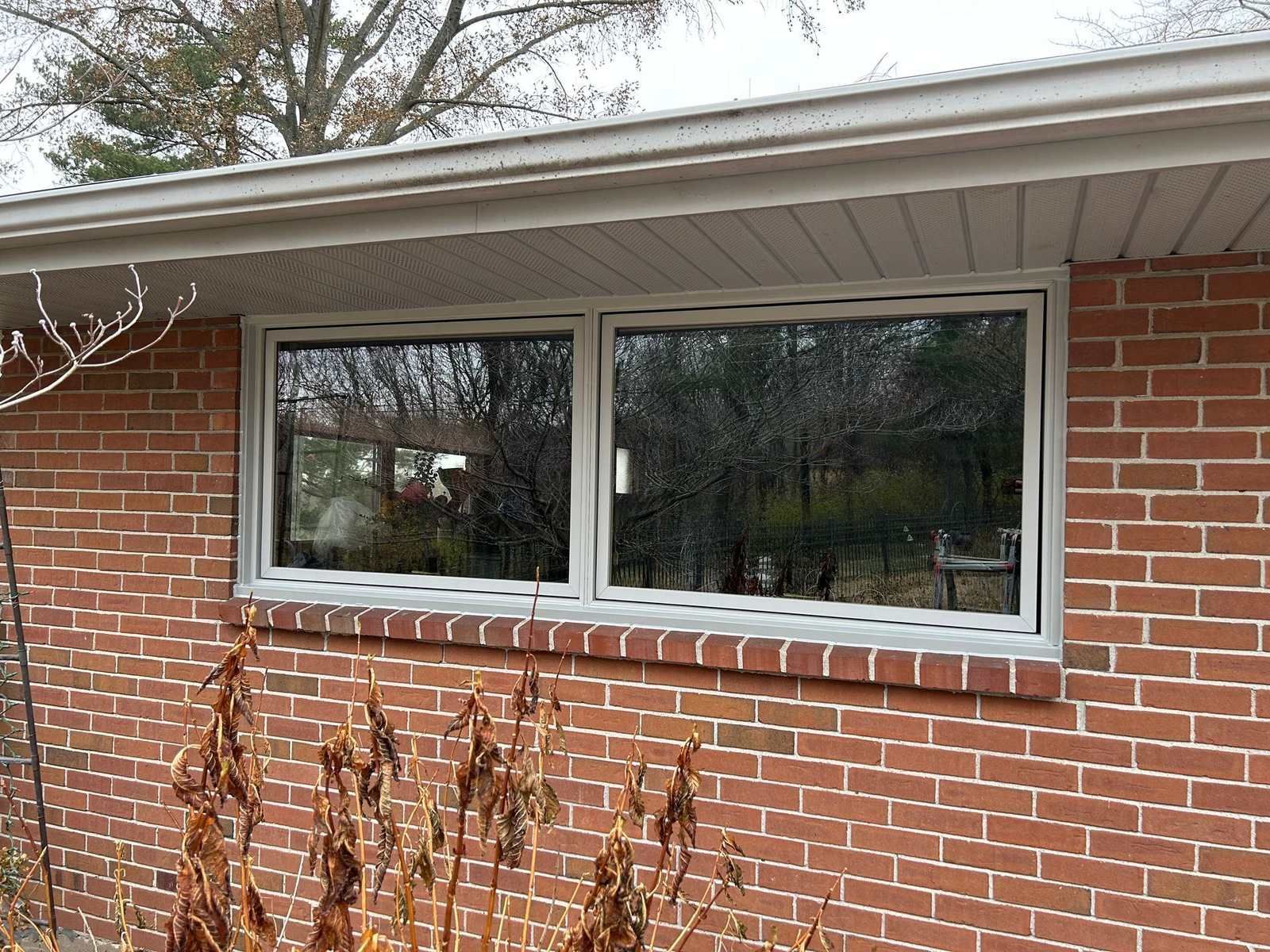 Two sliding windows with white frames on a brick ranch house