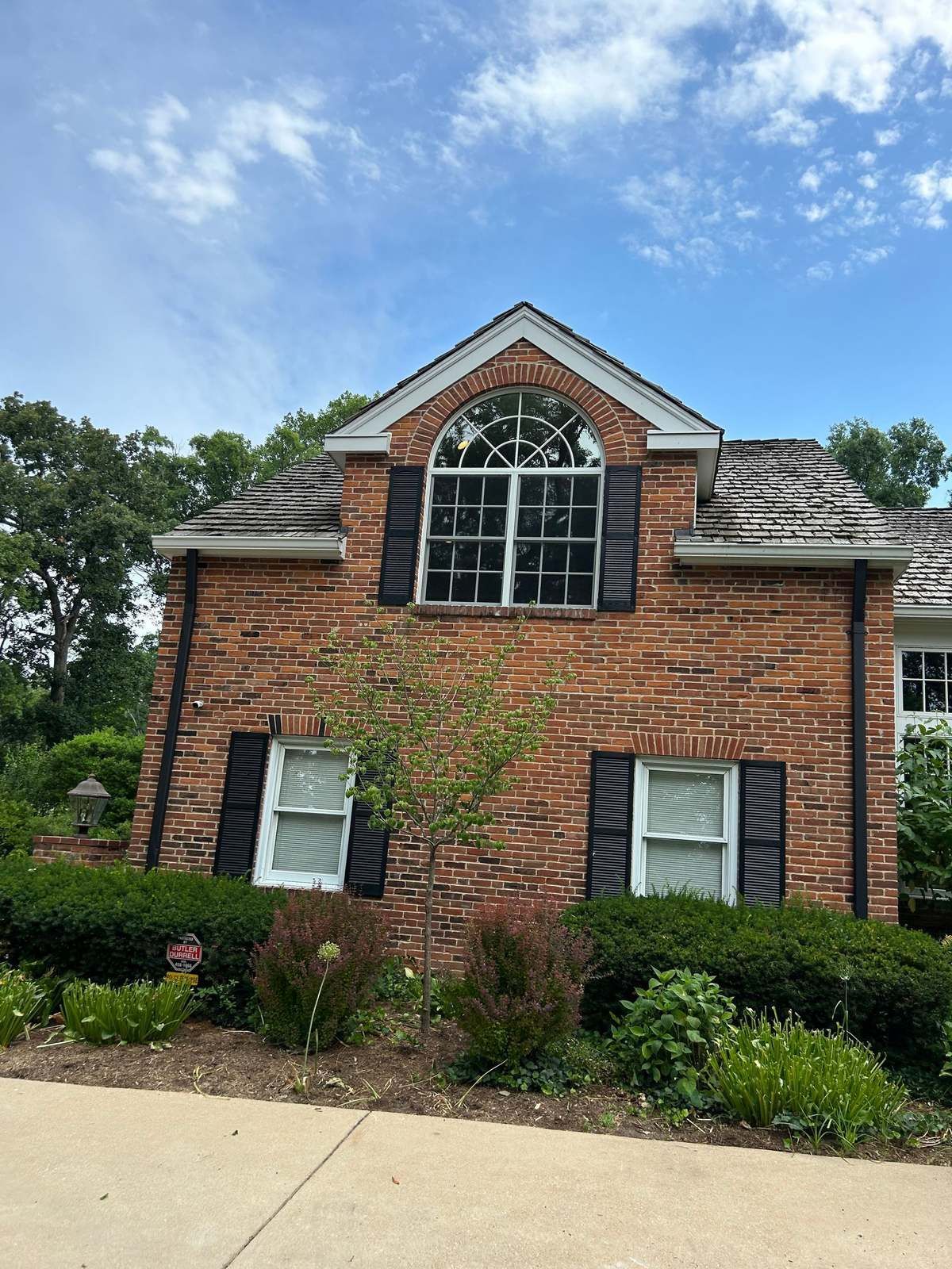 Brick house with a large arched gable window and black shutters