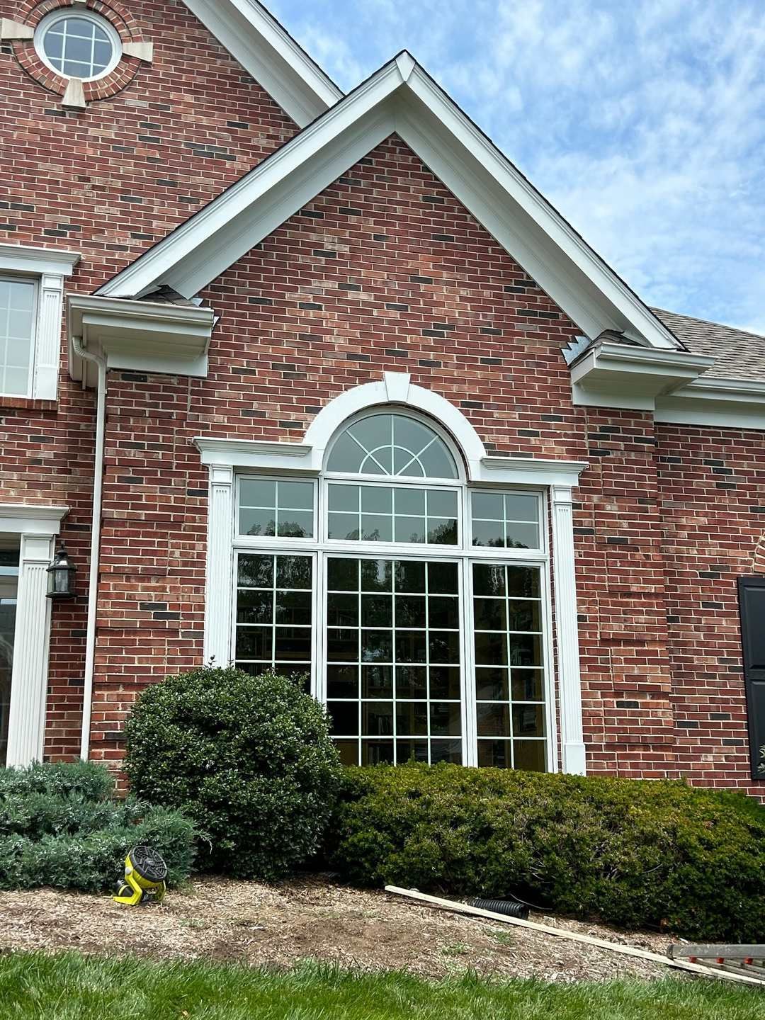 Large arched window with grilles below a brick gable