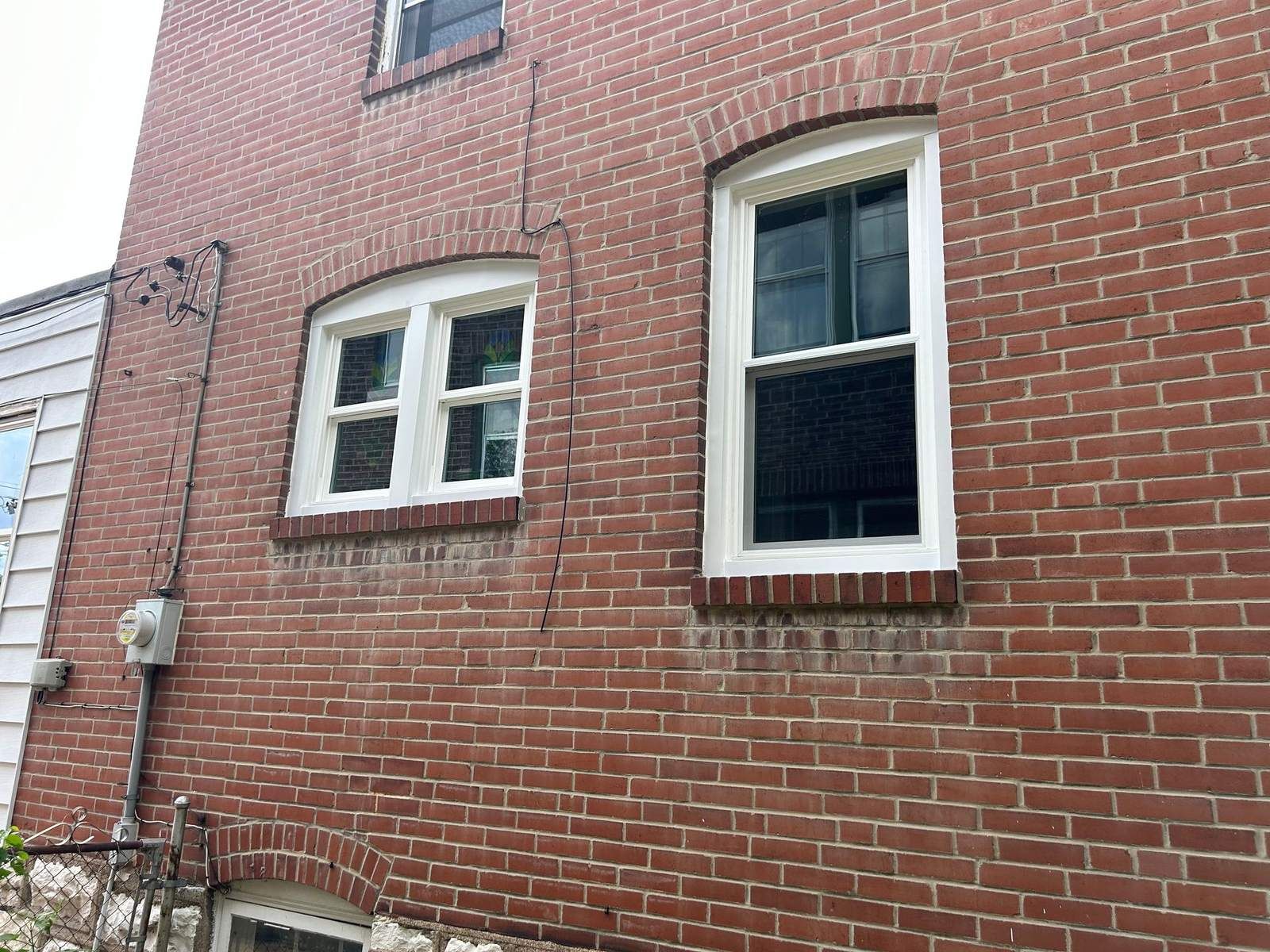 Arched-top replacement windows in a red brick wall