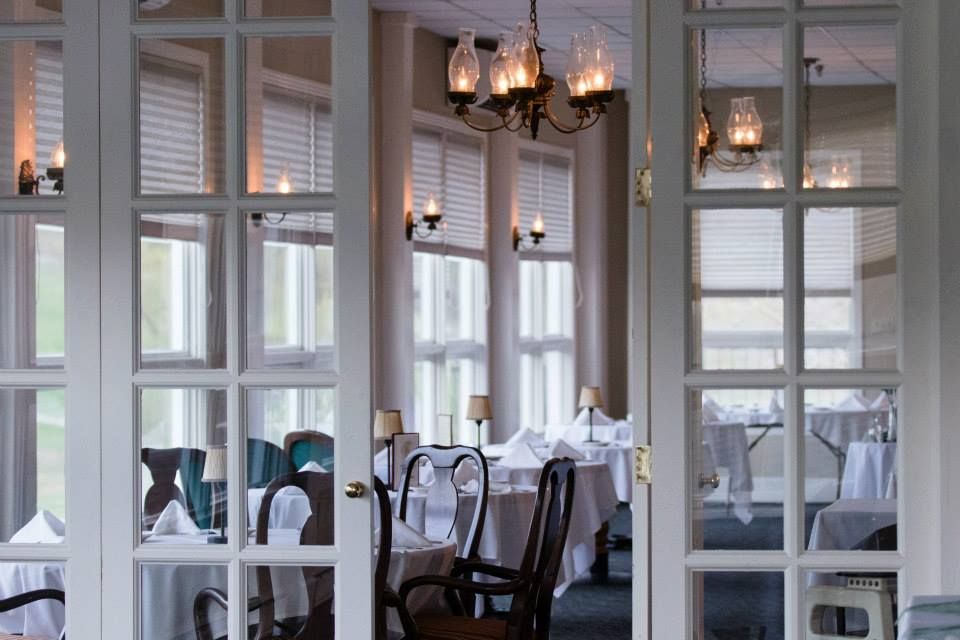 A long table with a blue tablecloth in a room with lots of windows. Set up for a meeting or banquet