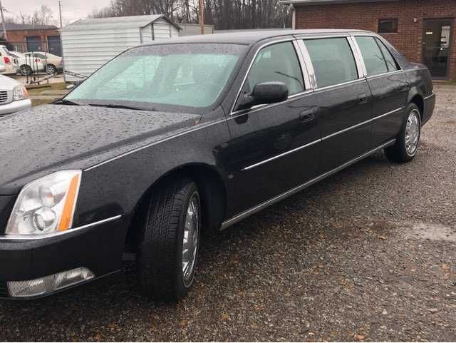 A black limousine is parked in front of a brick building.