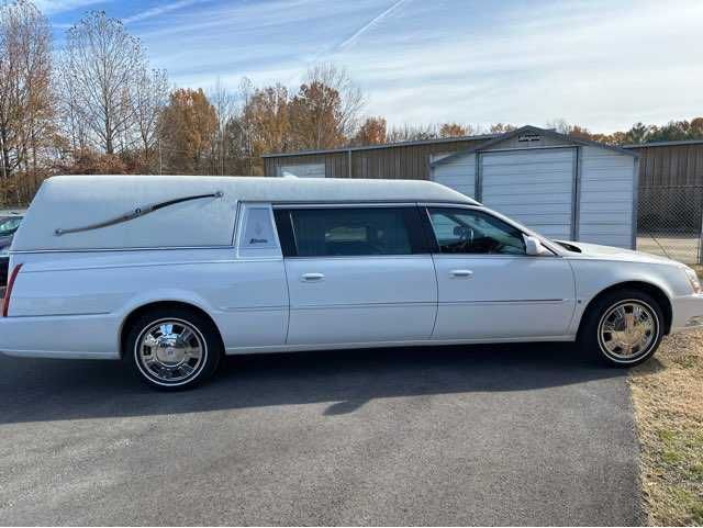 A white funeral car is parked on the side of the road.