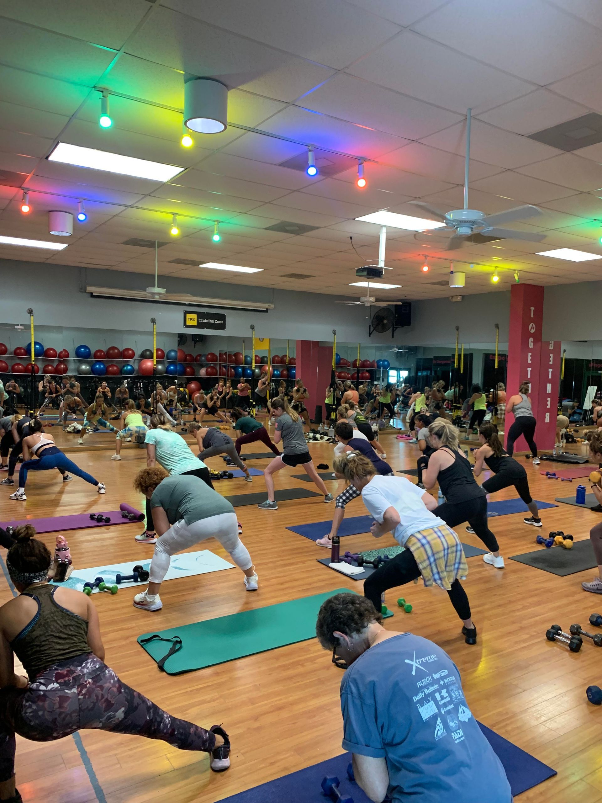 A group of people are doing exercises with pilates balls in a gym.
