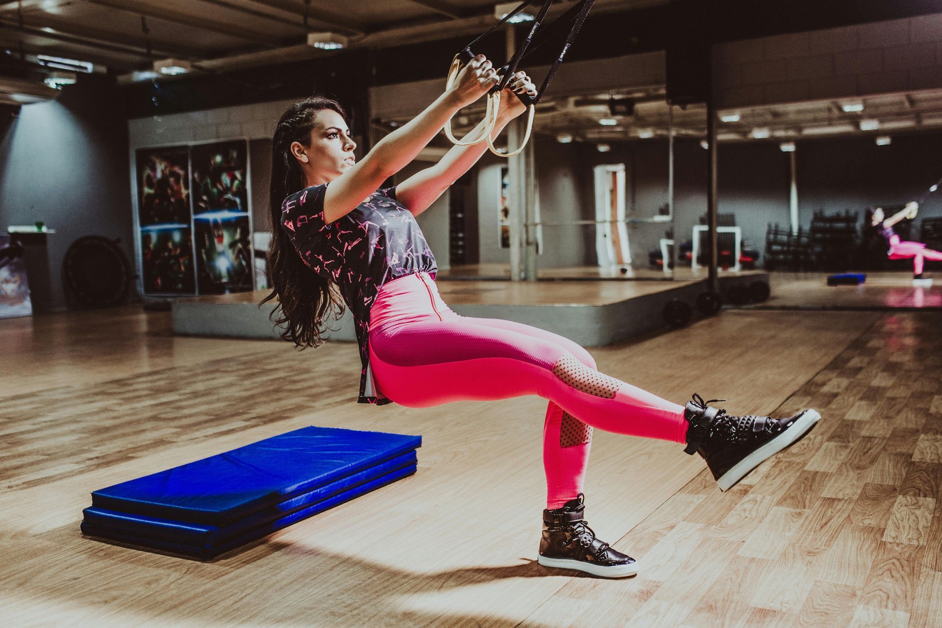 A woman is doing exercises on a rope in a gym.