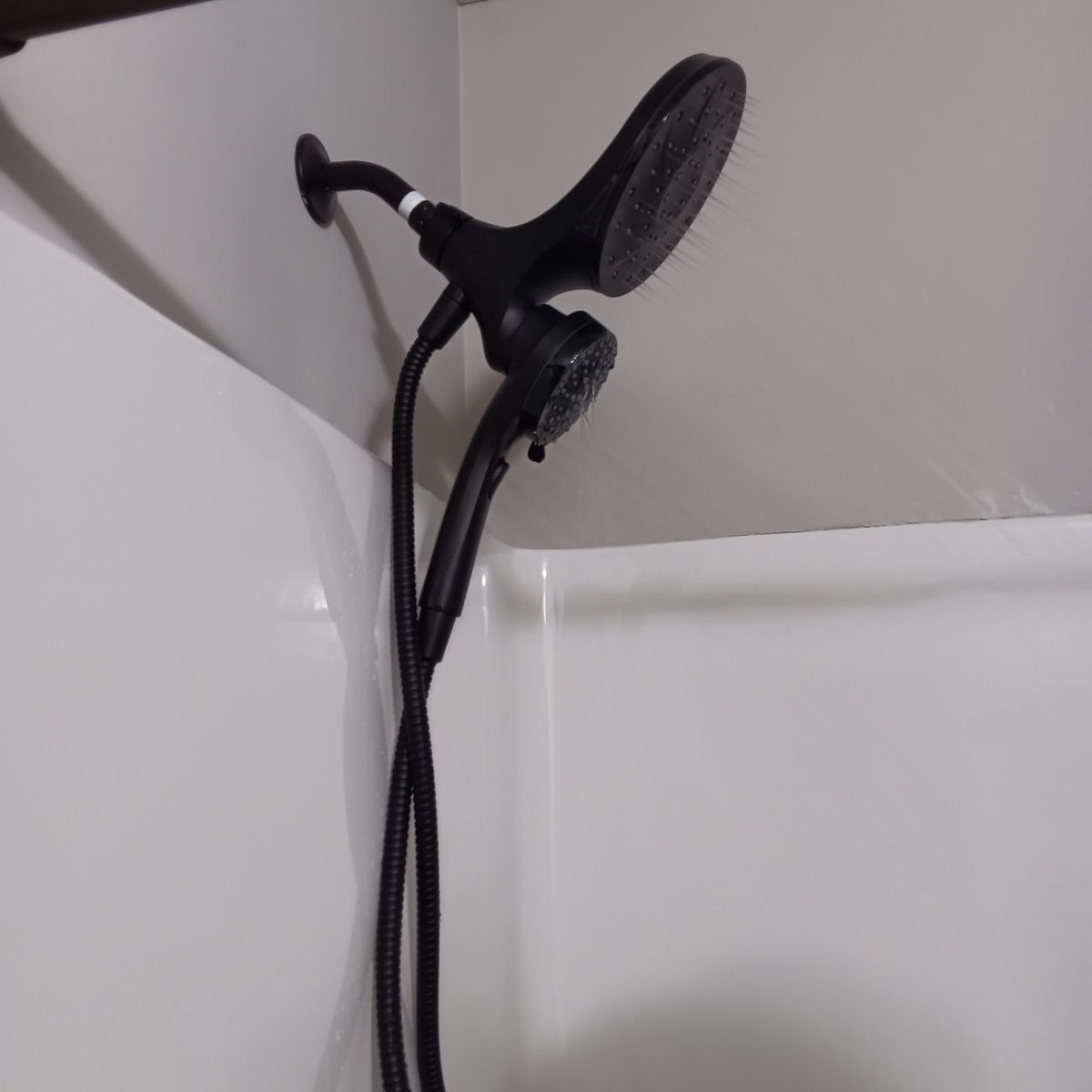 Black dual showerheads in a white shower stall.