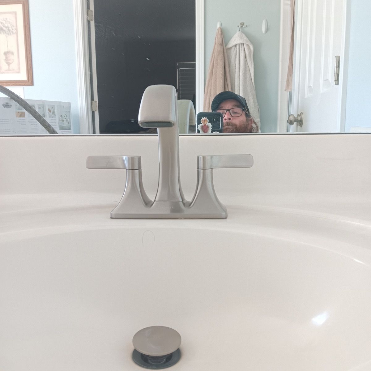 Bathroom sink with faucet, person taking photo in mirror reflection.