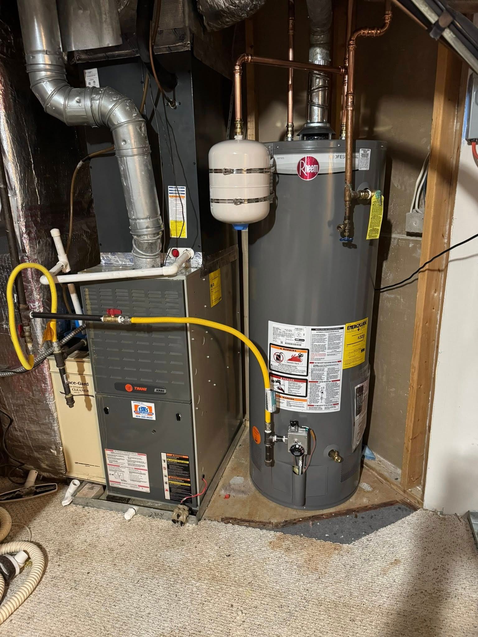 Furnace and water heater in a utility room. Copper pipes connect the water heater to an expansion tank.