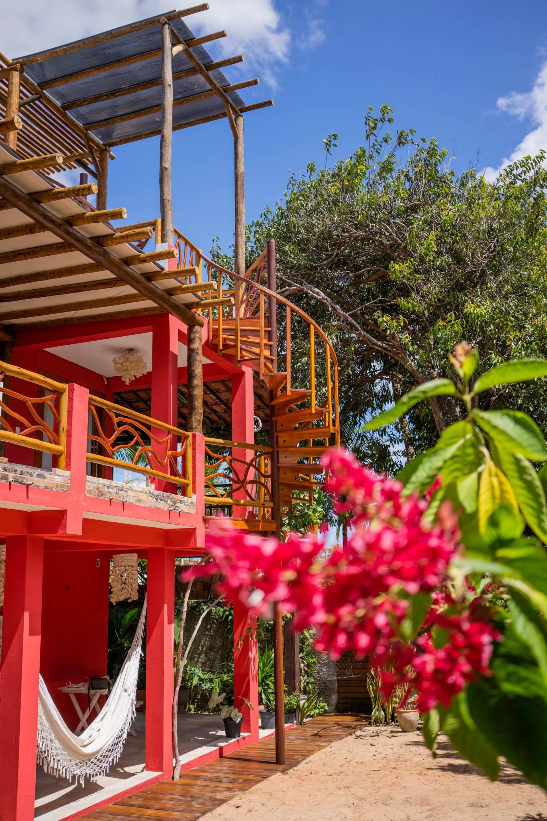 Uma casa vermelha com uma escada em espiral e uma rede na frente.