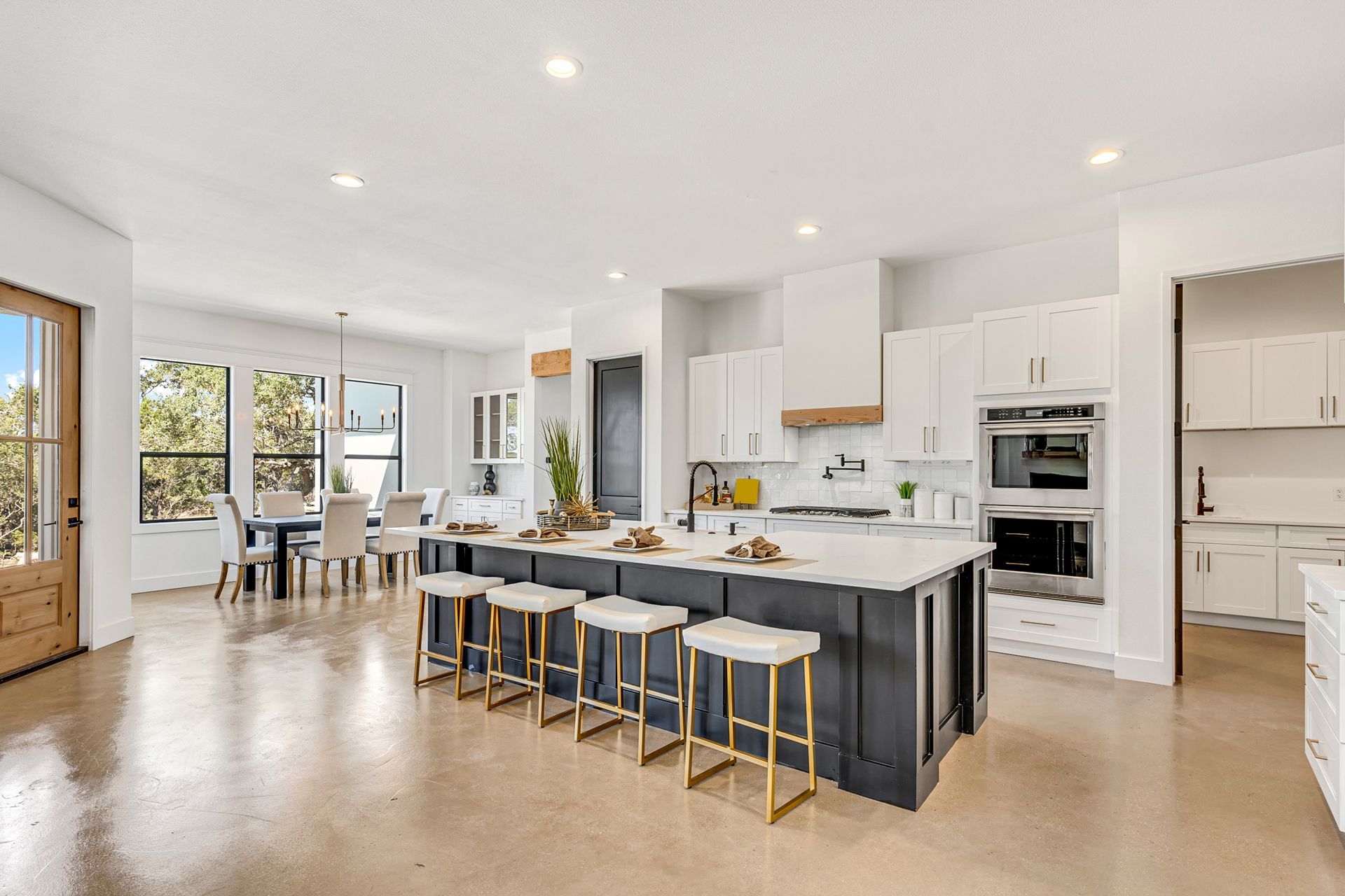 Spacious modern kitchen with island, seating, and dining area; white and dark blue cabinets, stainless steel appliances.