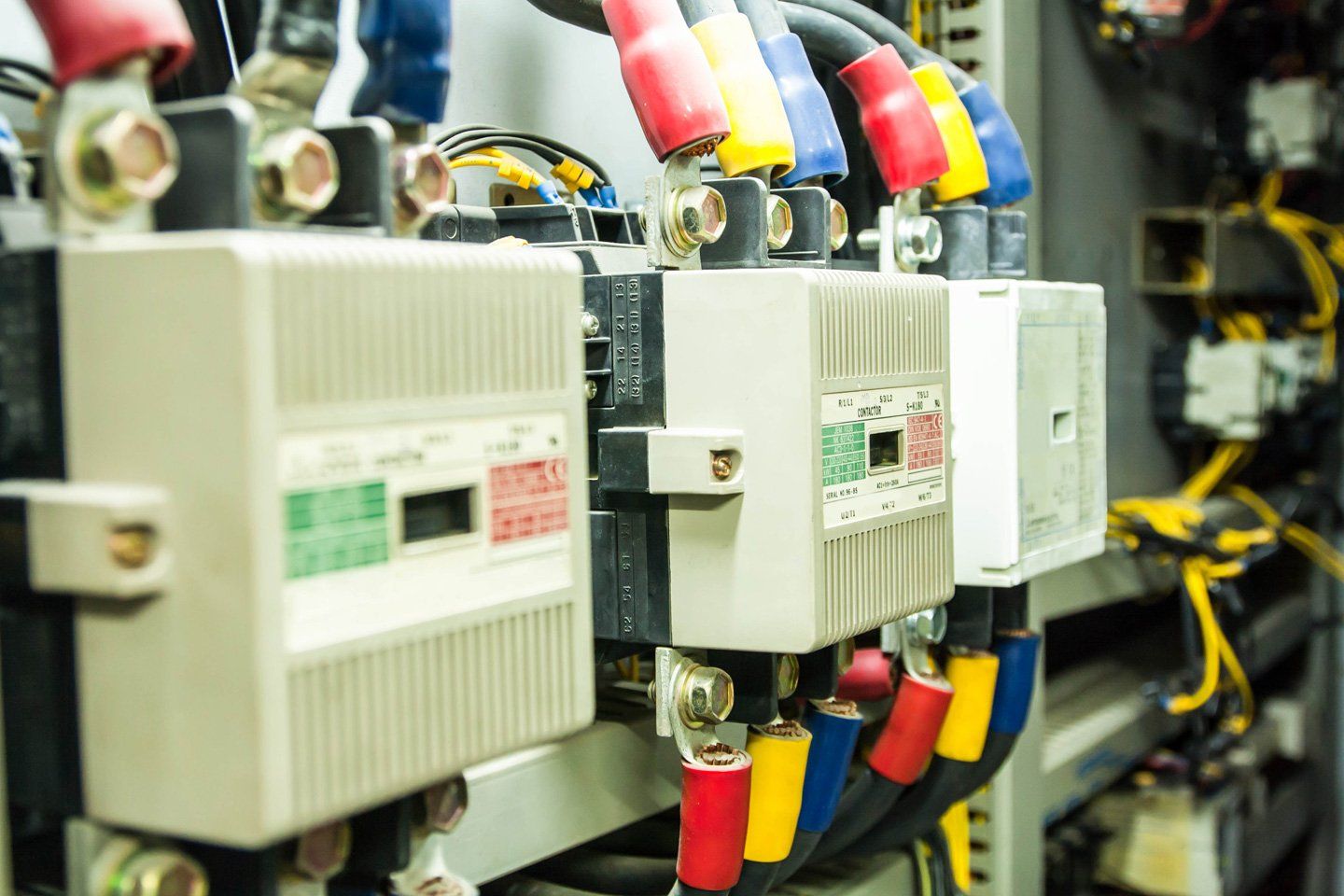 Quadro elettrico di controllo con fili colorati collegati a interruttori automatici bianchi all'interno di un contenitore metallico.