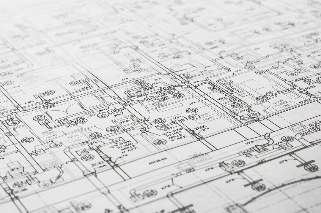 Primo piano di un disegno tecnico di ingegneria con intricate linee schematiche e annotazioni manoscritte su carta bianca.