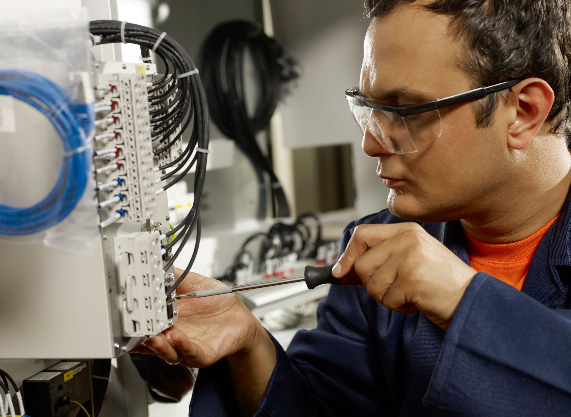 Un professionista al lavoro su un quadro elettrico, che utilizza un cacciavite per regolare i componenti del cablaggio.