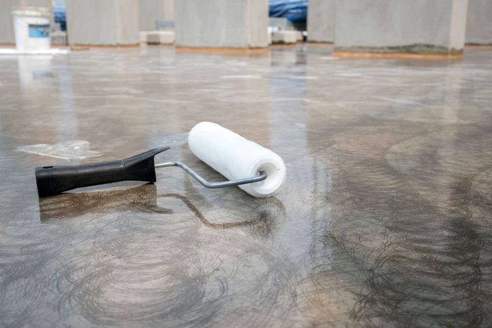 A White Paint Roller Rests on a Freshly Coated, Glossy Concrete Floor — Western Epoxy Works In Narromine, NSW
