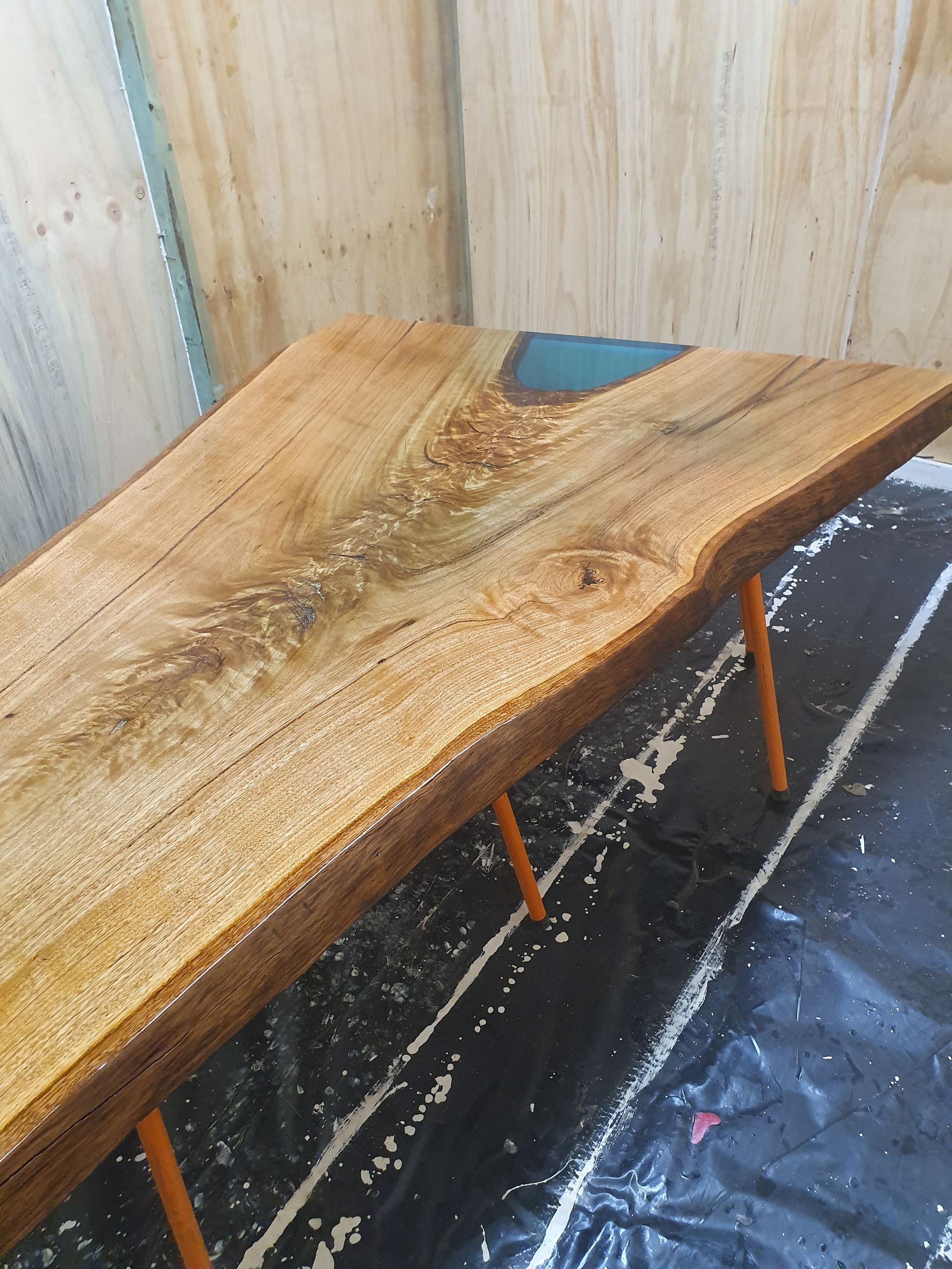 Wooden bench or table with a wet, worn surface in a small indoor corner with plywood walls