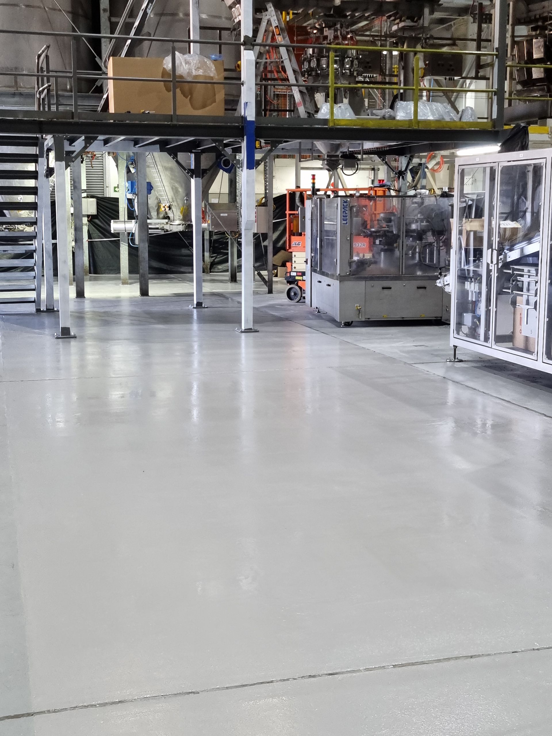Industrial factory floor with machinery, metal frames, and polished concrete walkway
