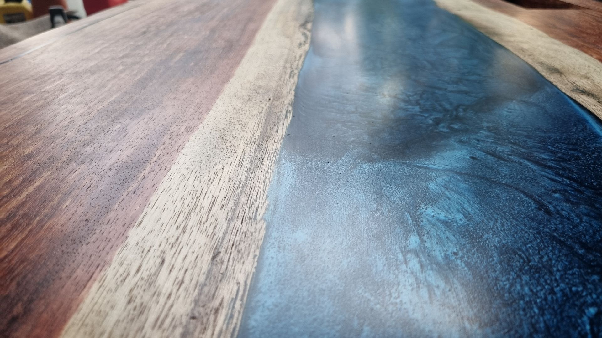 Close-up of a glossy blue and wood-grain painted surface with a textured white strip running through it