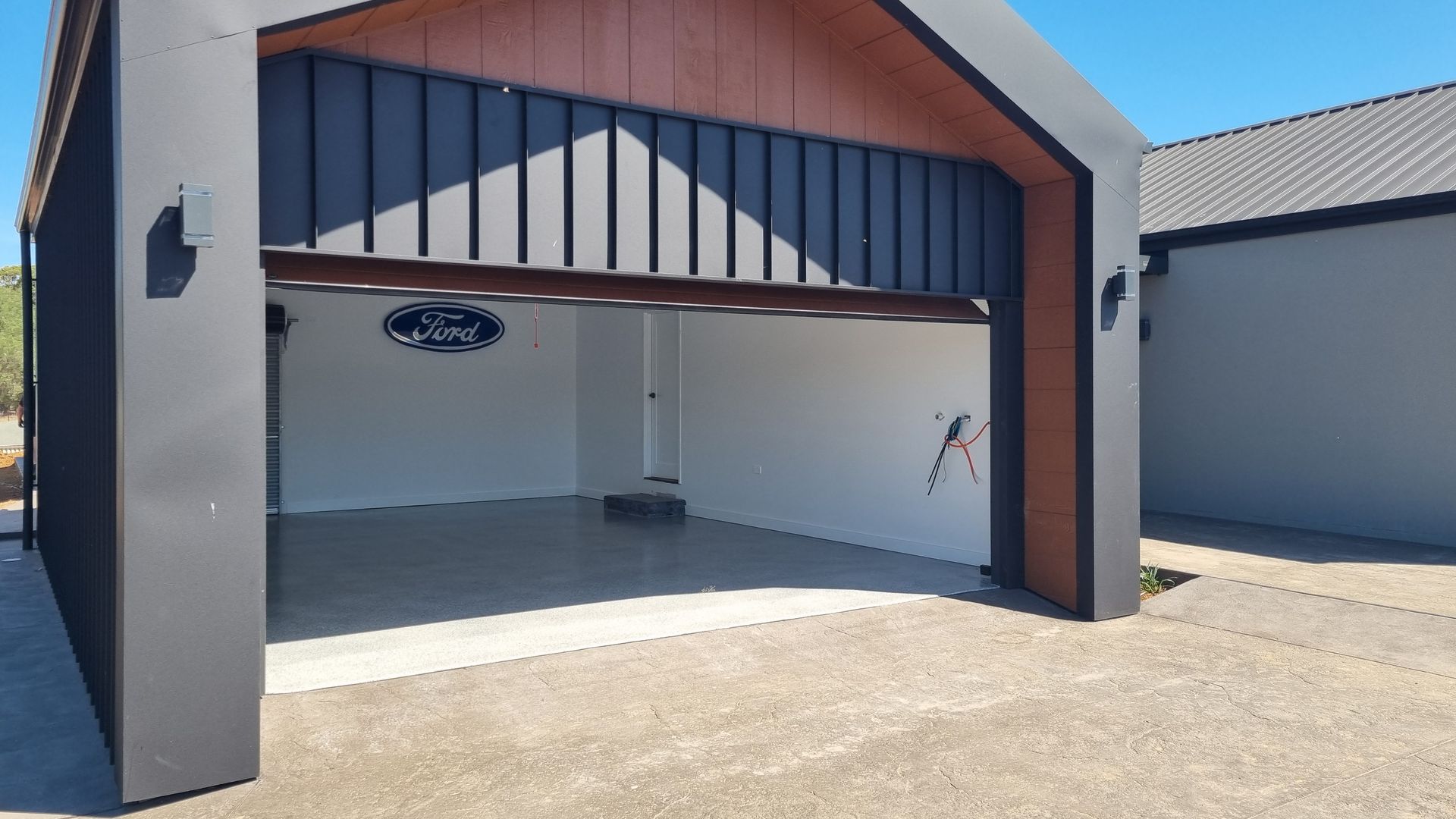 Open garage with blue trim, beige walls, and concrete floor in bright sunlight