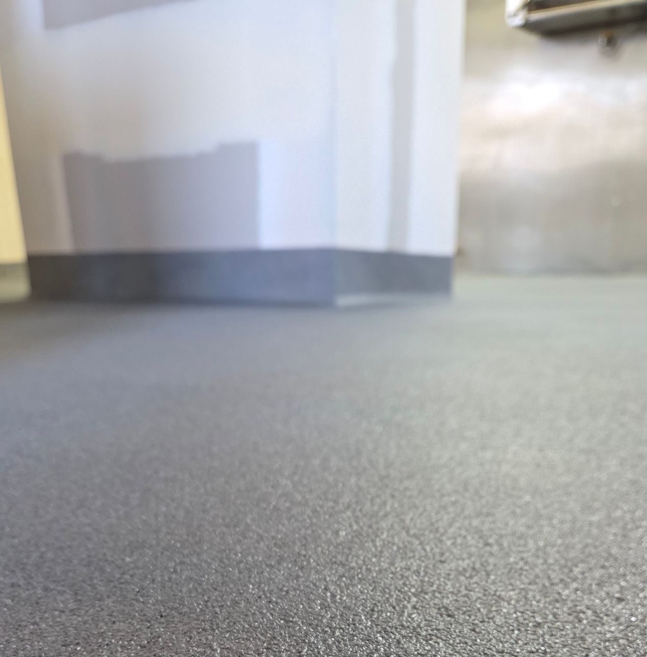 Low-angle view of a gray carpeted hallway with white walls and metal doorways