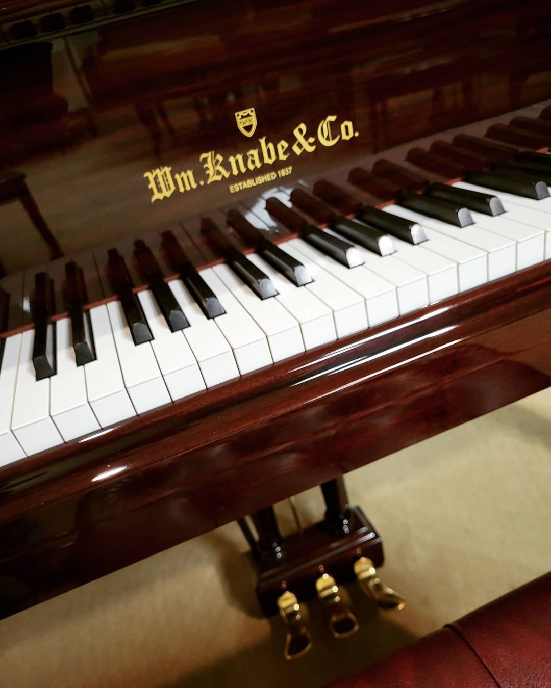 Polished upright piano with white and black keys and gold lettering on a dark wood finish