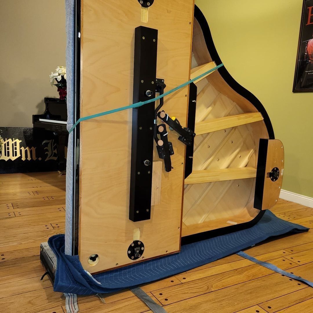 Wooden mechanical device with blue cord and black hardware on a blue base, indoors on a hardwood floor