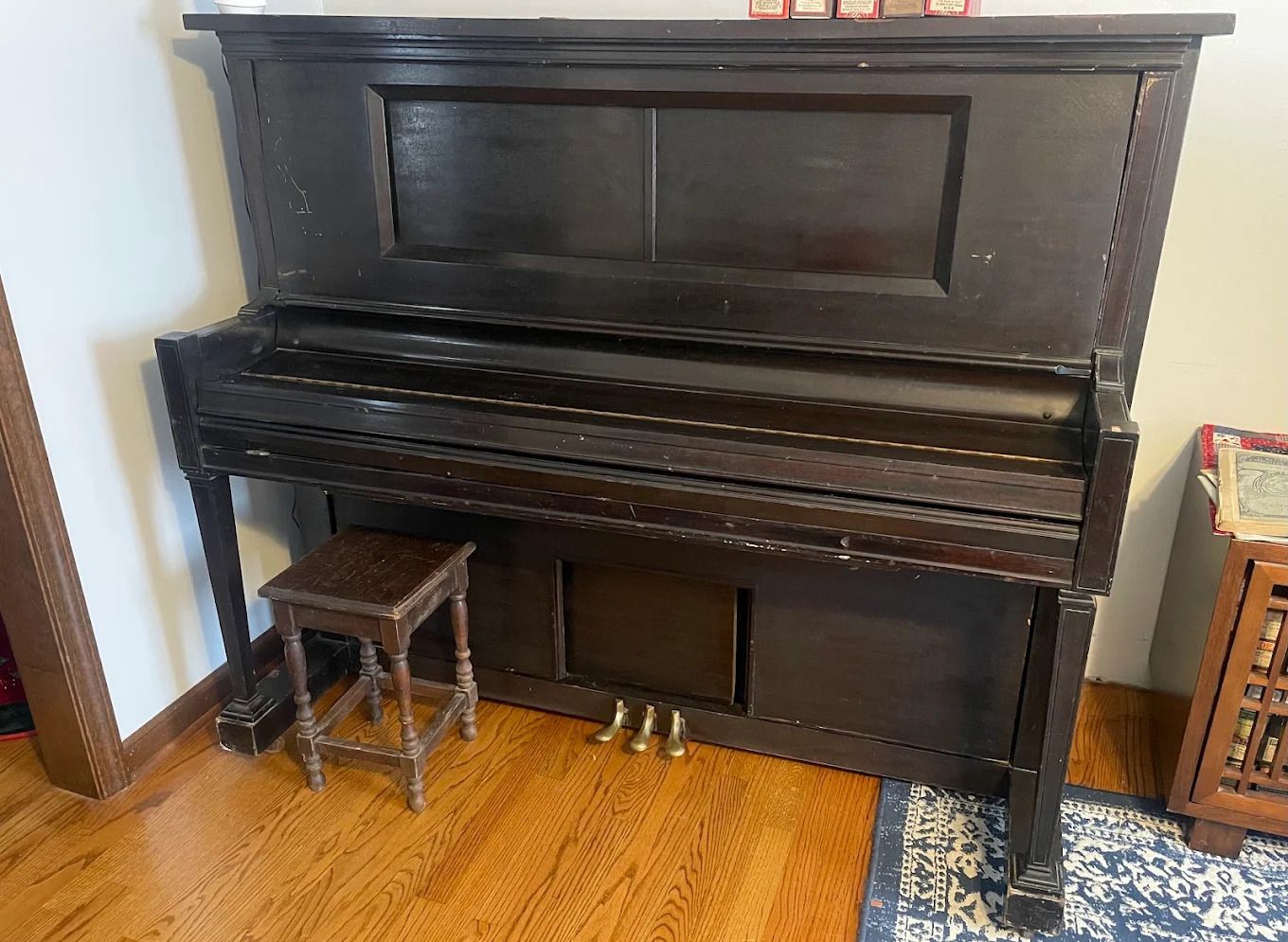 Black upright piano with bench in a hardwood-floored room