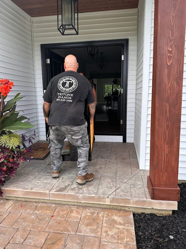 Person standing at a front porch doorway, viewed from behind, with white siding and brick steps.