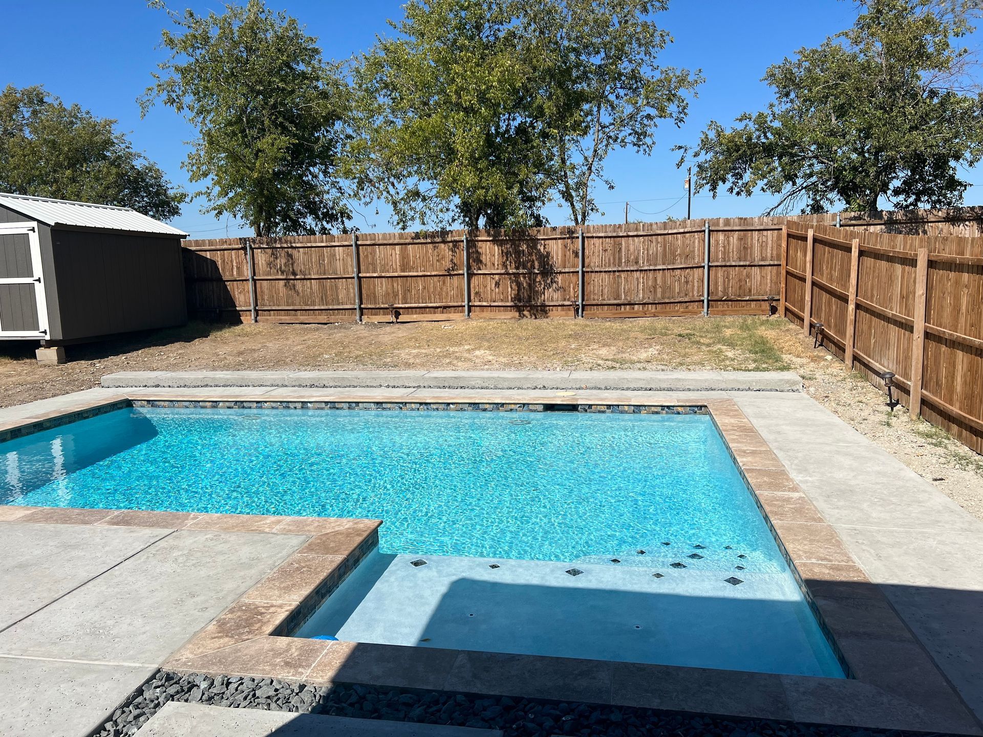 A large swimming pool with a wooden fence surrounding it