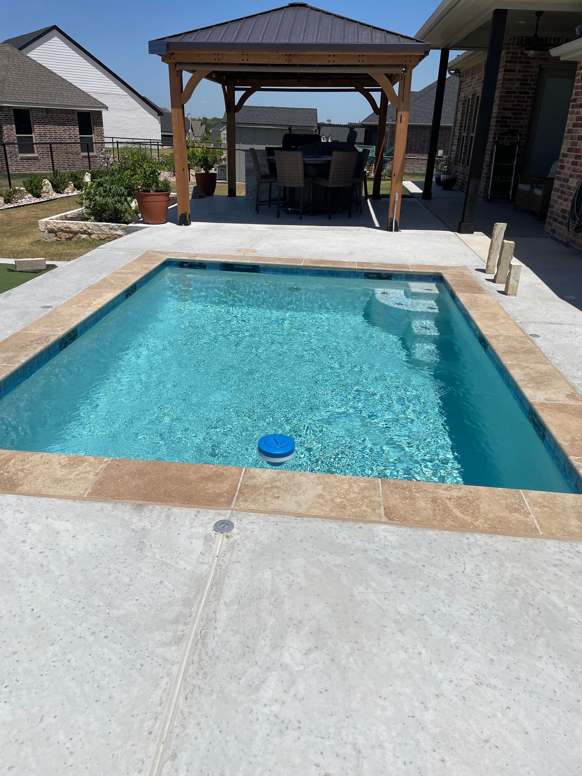 A large swimming pool with a gazebo in the background