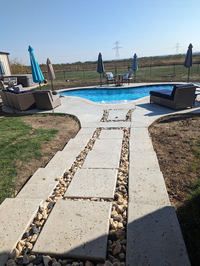 A walkway leading to a swimming pool with chairs and umbrellas