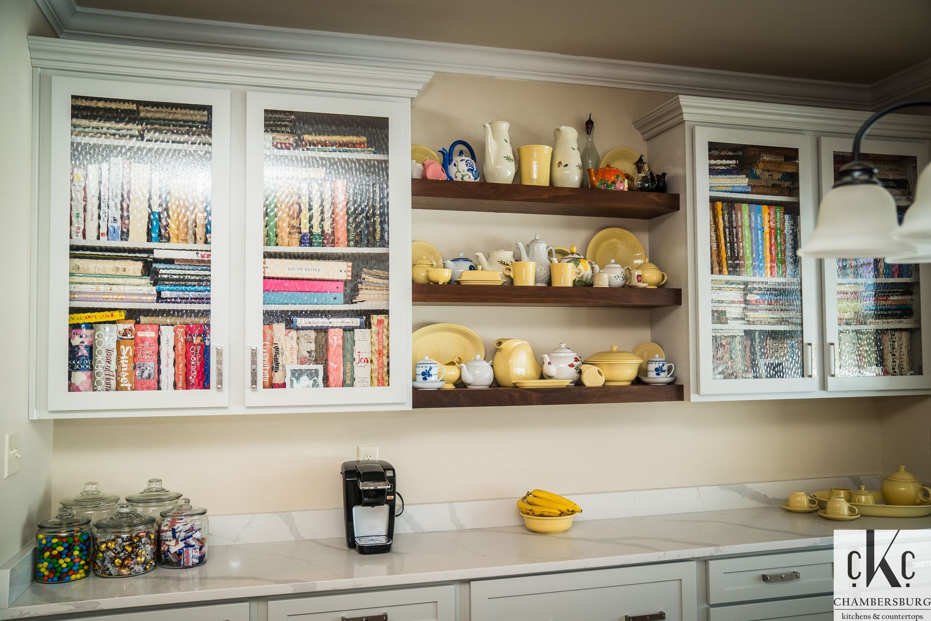 A kitchen with a lot of shelves and cabinets filled with dishes and books.