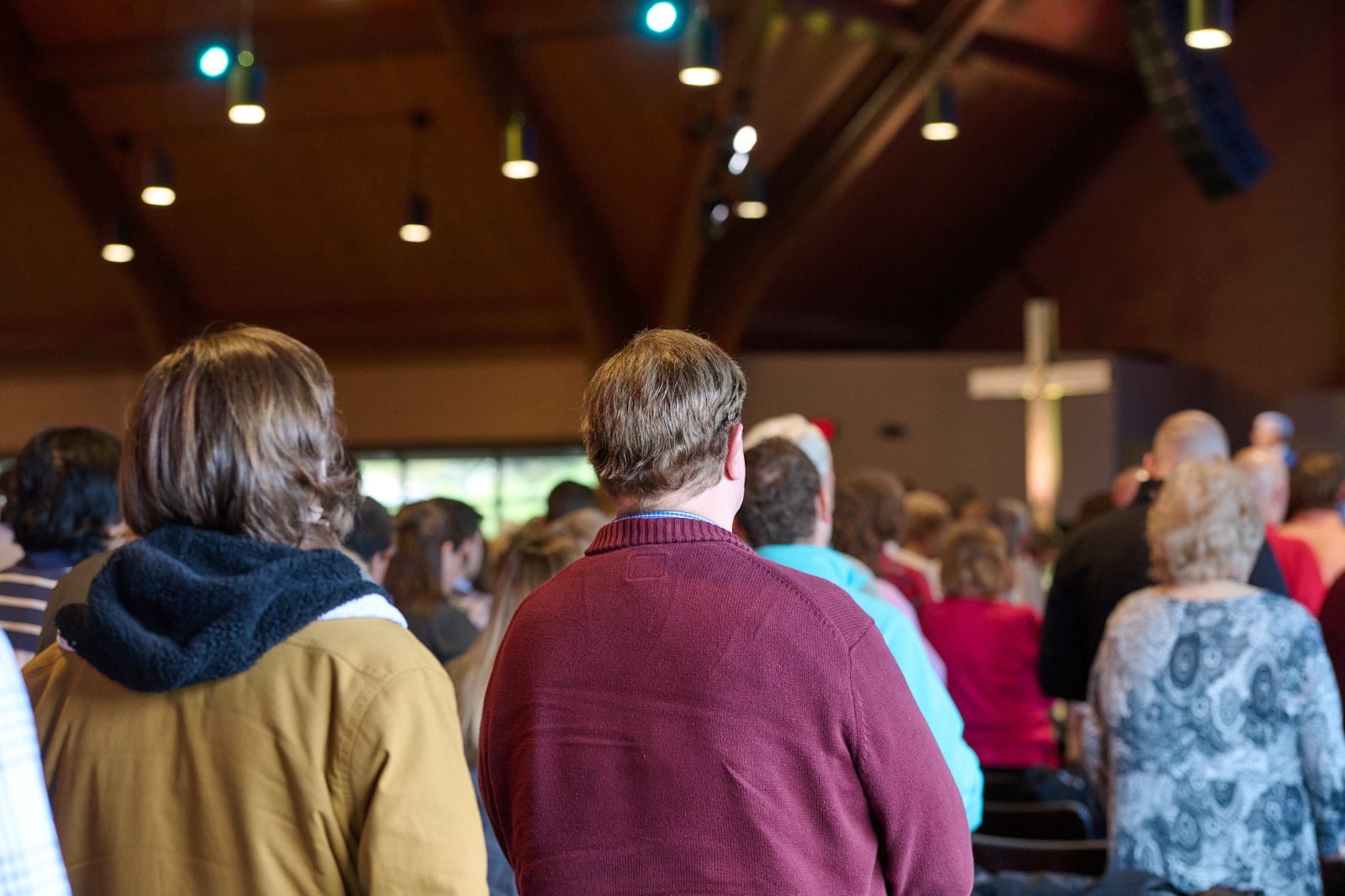 A group of people are standing in a church with a cross in the background.